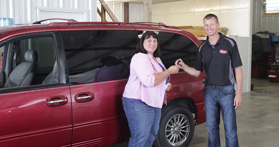Mark handing keys to a person at a Wheels to Prosper car giveaway event at Probst Auto Body
