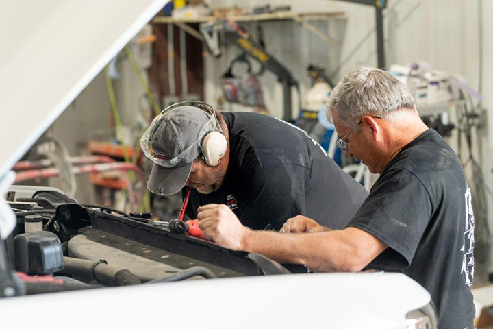 a body technician reassembles parts back on a car